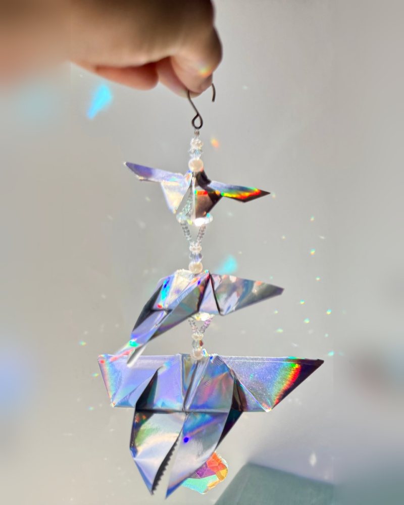 Holographic origami butterflies and a crystal drop on a beaded strand.