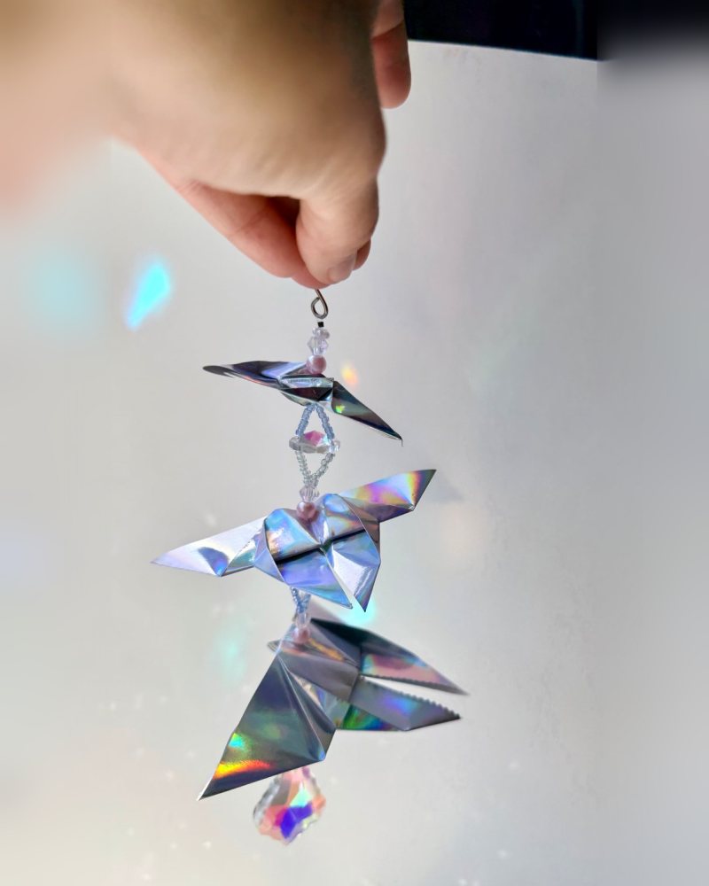 Holographic origami butterflies on a crystal strand, throwing rainbows.